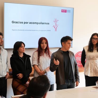 Jóvenes egresados presentan frente a una pantalla con el mensaje Gracias por acompañarnos