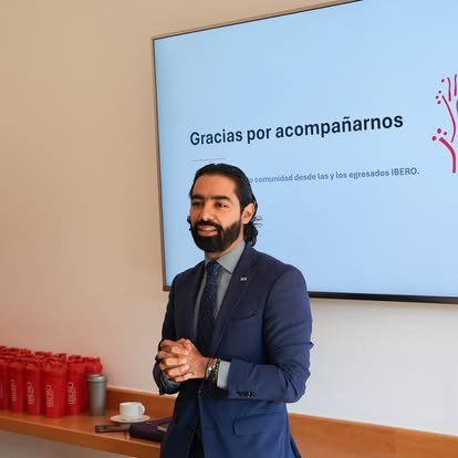 Egresado habla frente a una pantalla con el mensaje Gracias por acompañarnos