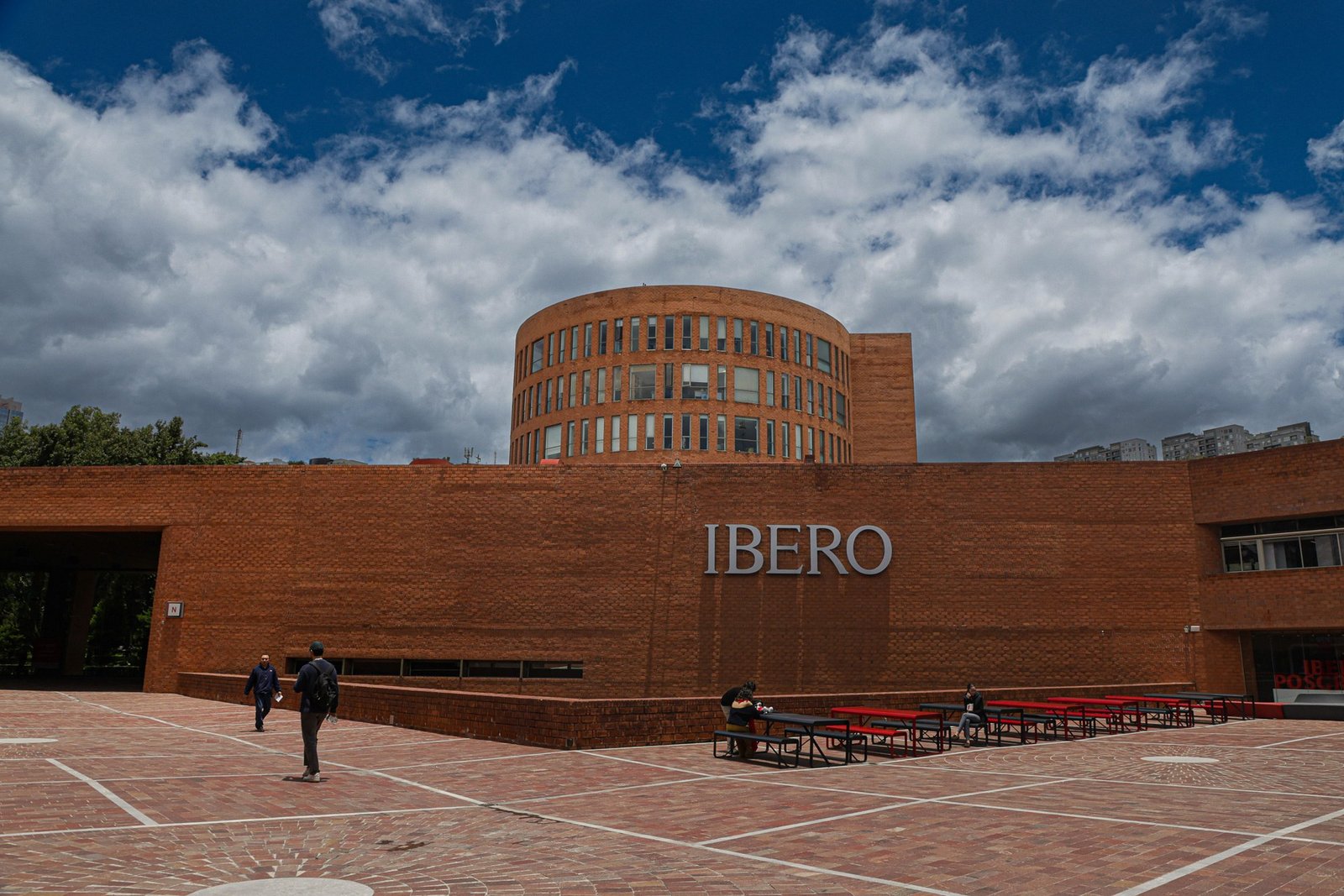 Edificio de ladrillo con el letrero IBERO en el campus de la Universidad Iberoamericana bajo un cielo con nubes